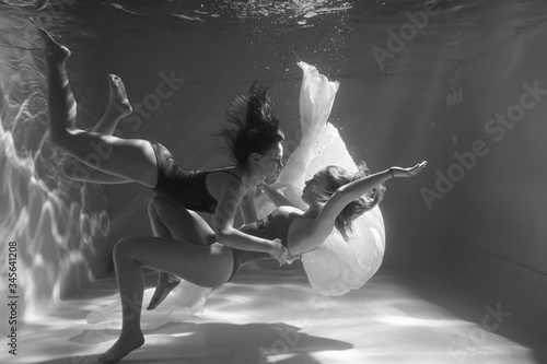 Two beautiful lesbian girls are swimming underwater. Attractiveness. Sexual poses and gestures. Female dance underwater. Swimwear and pool. Two mermaids. Two girlfriends women.Gay girls. Same-sex love