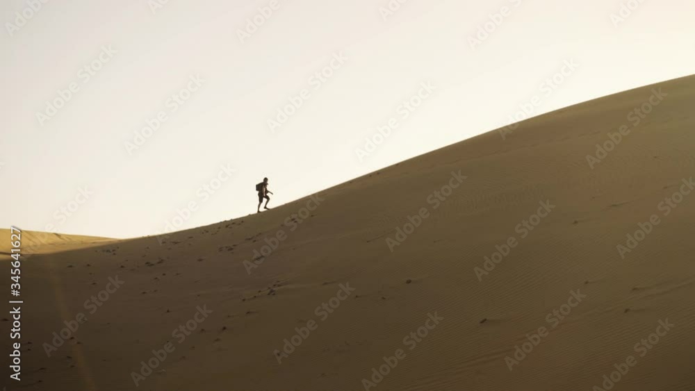Man Walking Up Sand Dune In Desert Man Walking Up Sand Dune In Desert