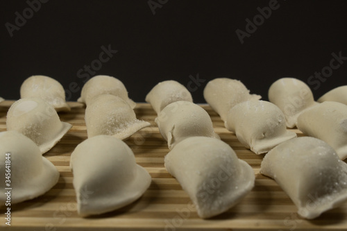 Raw dumplings, pierogi or pyrohy, varenyky, vareniki, served with cottage cheese on board. National Russian cuisine, natural organic homemade bakery product, view from above.