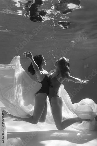 Two beautiful lesbian girls are swimming underwater. Attractiveness. Sexual poses and gestures. Female dance underwater. Swimwear and pool. Two mermaids. Two girlfriends women.Gay girls. Same-sex love