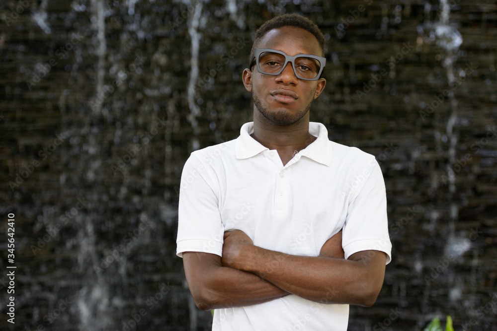 Portrait of young African nerd man with arms crossed in the city outdoors Portrait of young African nerd man with arms crossed in the city outdoors