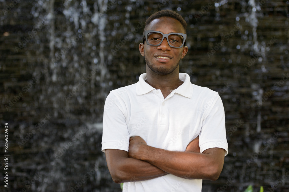 Portrait of happy young African nerd man smiling with arms crossed outdoors Portrait of happy young African nerd man smiling with arms crossed outdoors