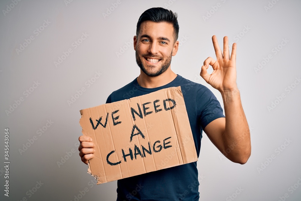 Young handsome activist man protesting for the enviroment hoding cardboard doing ok sign with fingers, excellent symbol Young handsome activist man protesting for the enviroment hoding cardboard doing ok sign with fingers, excellent symbol