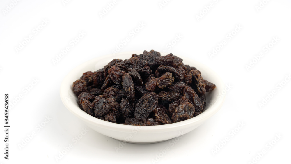 Dried black raisin in white bowl isolated in white background. Dried black raisin in white bowl isolated in white background.