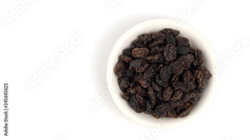 Dried black raisin in white bowl isolated in white background.