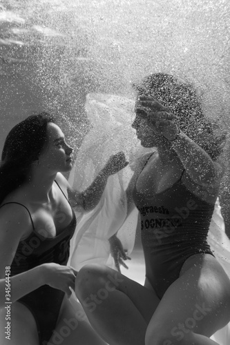 Two beautiful lesbian girls are swimming underwater. Attractiveness. Sexual poses and gestures. Female dance underwater. Swimwear and pool. Two mermaids. Two girlfriends women.Gay girls. Same-sex love