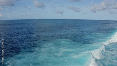 Aerial view of blue ocean with beautiful foaming rolling waves at sunny day