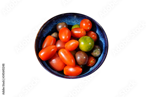 a group of colorful organic tomatoes in a bowl with white background 