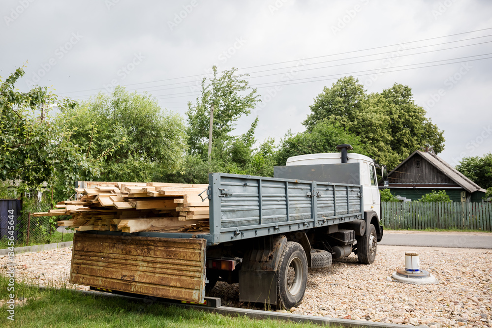 A planed board lies on board the truck. Building materials were brought to the construction site. Chopped wood for interior use.