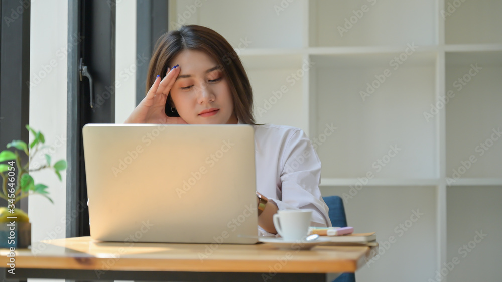 A young woman uses a laptop for work,She works from home and is tired. A young woman uses a laptop for work,She works from home and is tired.