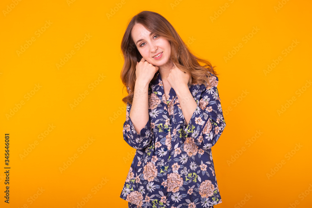 Excited young woman with curly hair in home wear pajama, widely smiling having fun. Isolated on yellow background. Excited young woman with curly hair in home wear pajama, widely smiling having fun. Isolated on yellow background.