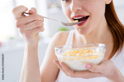 Closeup cropped photo of pretty housewife lady sit morning kitchen have breakfast eat cereal corn flakes milk stay home distance remote work good mood quarantine time indoors