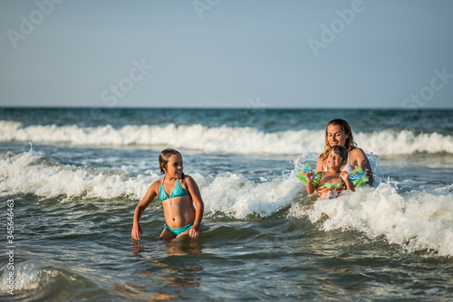 Cheerful young mother swims in the sea with her charming little daughters and enjoy the long-awaited weekend on a sunny summer day. Concept family vacation.