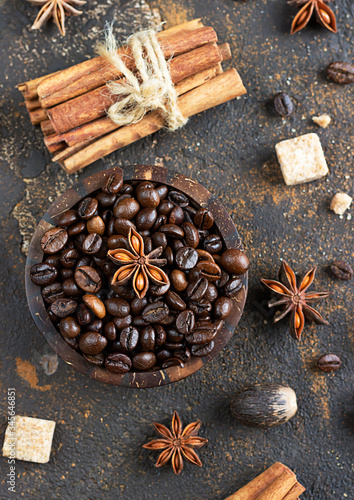 Aromatic set of coffee beans, anise stars, cinnamon sticks, brown sugar cubes and nutmeg on dark brown concrete background. Spices for Christmas cakes or drinks.