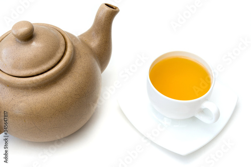 Wallpaper Mural Old light brown clay teapot with cracks and scratches on white background. White porcelain cup with green tea is next to it. Torontodigital.ca