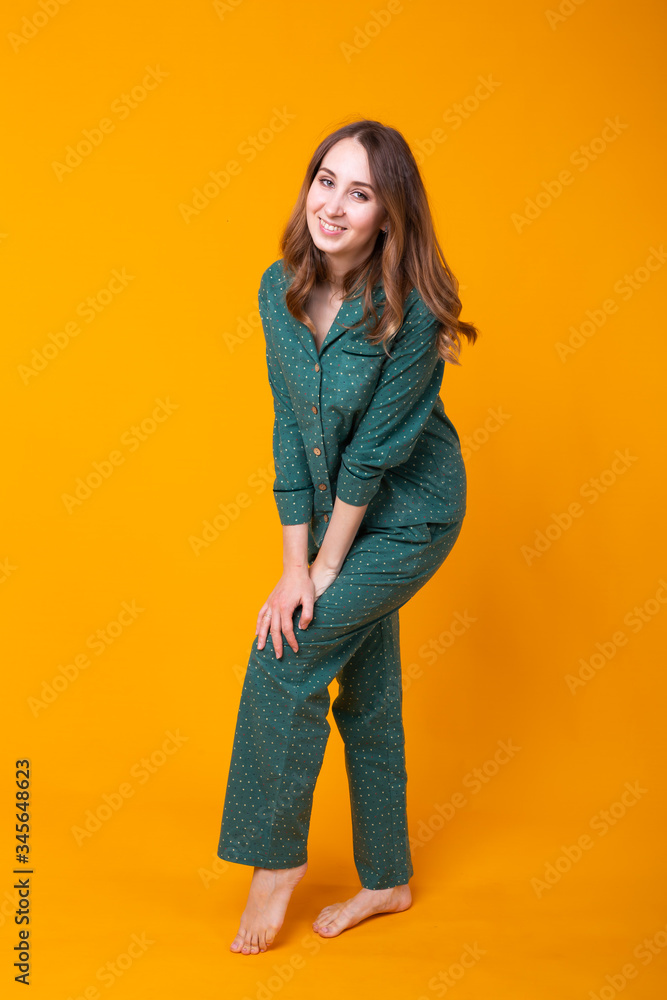 Smiling young girl in pajamas home wear posing while resting at home isolated on yellow background studio portrait. Relax good mood lifestyle concept. Smiling young girl in pajamas home wear posing while resting at home isolated on yellow background studio portrait. Relax good mood lifestyle concept.