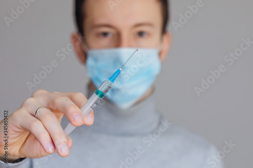 male medical worker in a mask holding a syringe, close up hand w