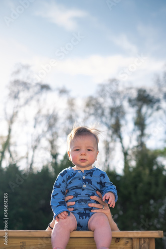 Portrait of a baby boy sitting on a ledge outside