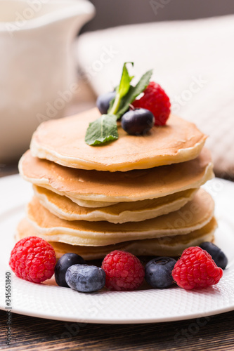 Pancakes with blueberries and raspberry on wooden background. Breakfast and traditional meal.