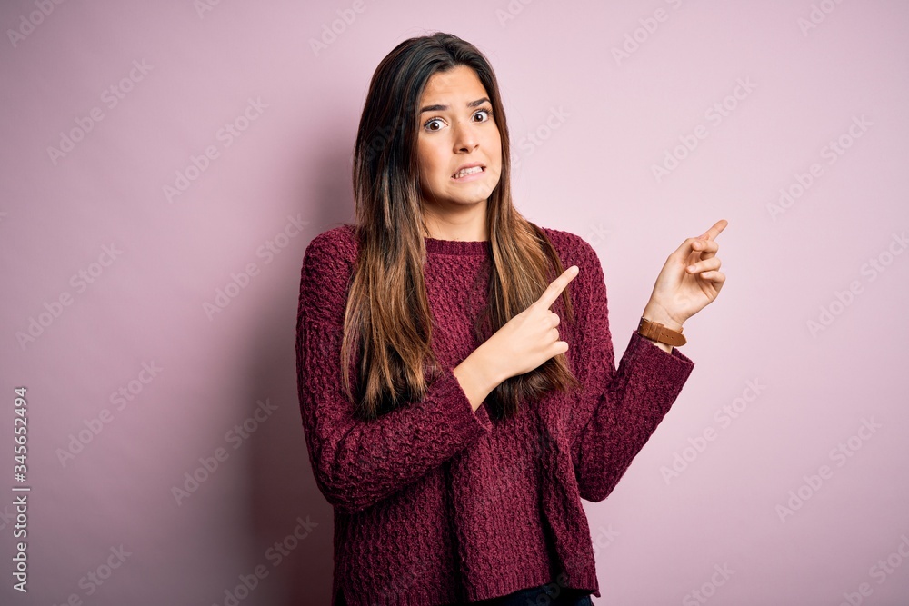 Young beautiful girl wearing casual sweater over isolated pink background Pointing aside worried and nervous with both hands, concerned and surprised expression Young beautiful girl wearing casual sweater over isolated pink background Pointing aside worried and nervous with both hands, concerned and surprised expression