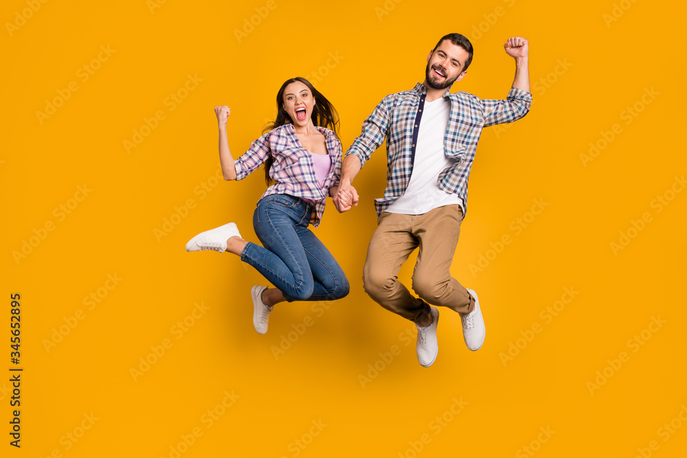 Full length photo ecstatic crazy woman man jump enjoy rejoice lucky covid-19 victory news raise fists scream yes wear checkered plaid shirt trousers isolated bright shine color background