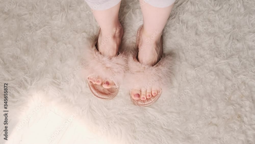 Female feet in fluffy pink slippers dancing toes. Cozy house, stay home. Female feet in fluffy pink slippers dancing toes. Cozy house, stay home.