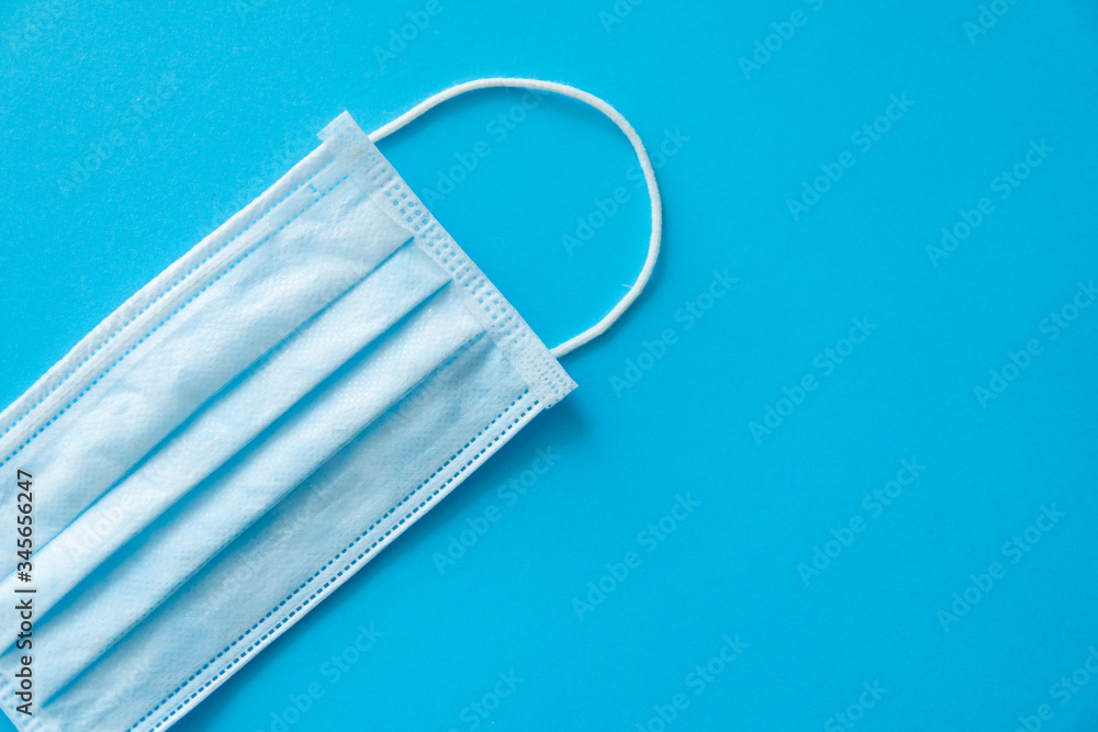Medical protective mask isolated on blue background. Disposable 3-ply medical mask to cover the mouth and nose to prevent coronavirus. Procedure mask from bacteria. Coronavirus quarantine. Medical protective mask isolated on blue background. Disposable 3-ply medical mask to cover the mouth and nose to prevent coronavirus. Procedure mask from bacteria. Coronavirus quarantine.