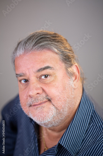 Closeup portrait of a latin man. He is looking up at the camera. He is serious and looks disappointed.