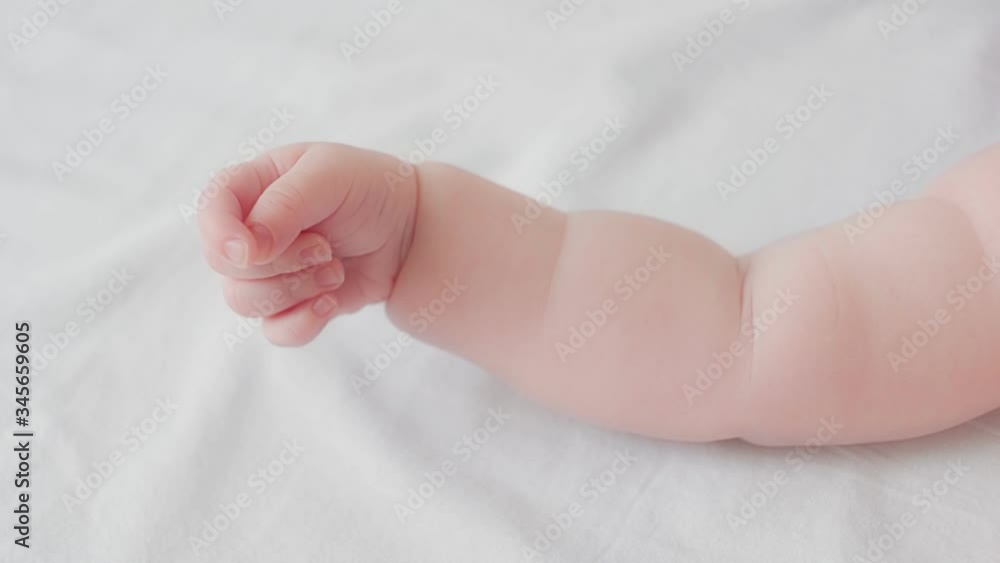 Close up cute little naked hand of adorable toddler baby lying on soft white bed top view