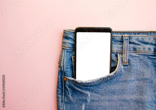 White screen smartphone in jeans pocket. Smartphone place for text. Smartphone in a pocket on a pink background.  Copy Space
