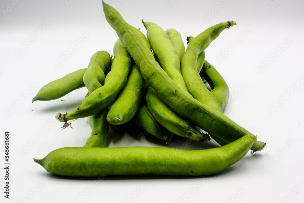 pile of fresh green broad beans in their shells isolated on a white background pile of fresh green broad beans in their shells isolated on a white background