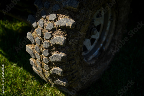 Off road vehicle detail with tire full of mud on a green grass