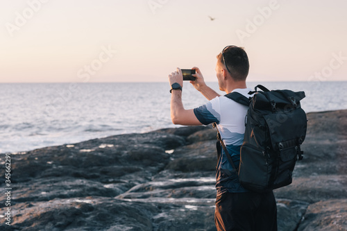 man taking photos of sunset with mobile phone