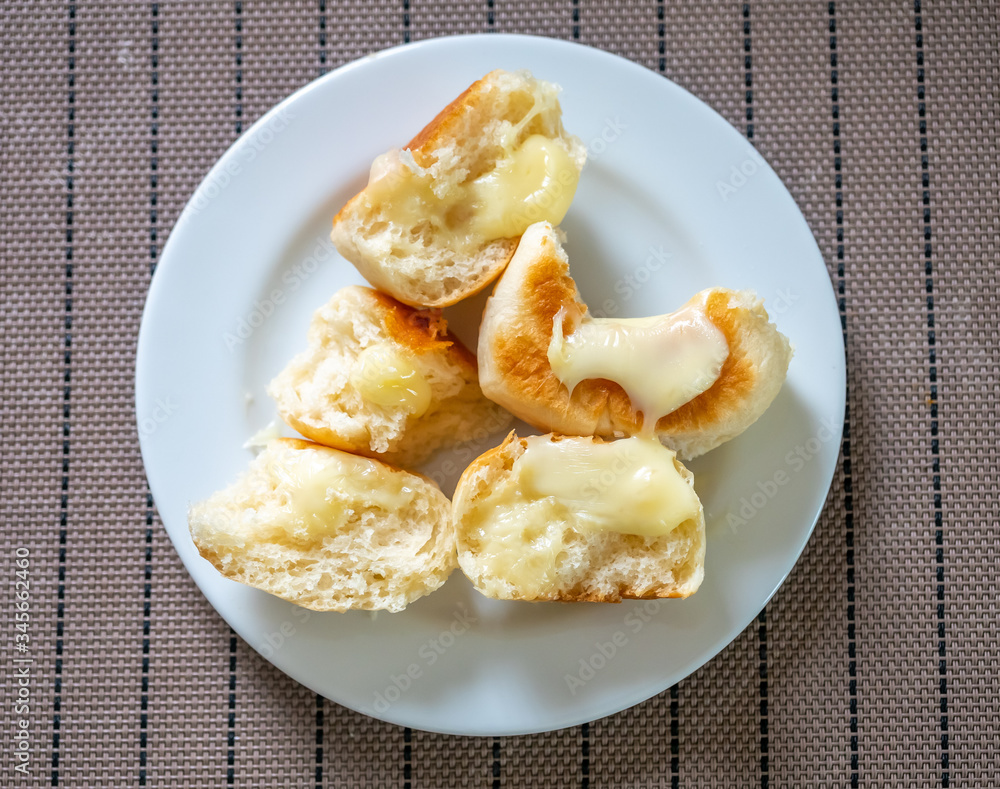 Homemade buns topping with melting milk cheese on white plate, top view Homemade buns topping with melting milk cheese on white plate, top view
