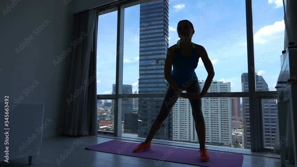 Silhouette of young sexy woman exercising by window at home, slow motion Silhouette of young sexy woman exercising by window at home, slow motion