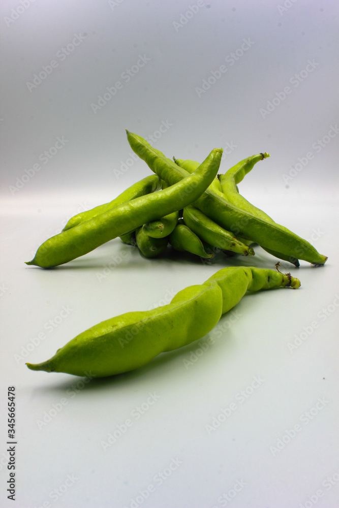 pile of fresh green broad beans in their shells isolated on a white background pile of fresh green broad beans in their shells isolated on a white background
