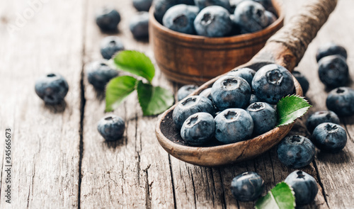 Blueberries in wooden spoon on old wood table. Healthy eating and nutrition concept.