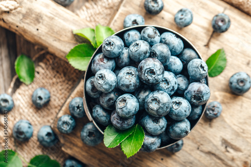 Freshly picked blueberries in bowl on wooden background. Healthy eating and nutrition.