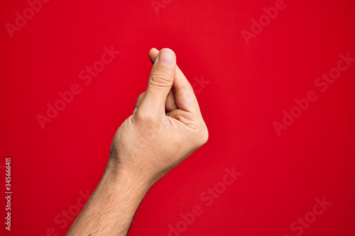 Hand of caucasian young man showing fingers over isolated red background holding blank space with thumb finger, business and advertising photo