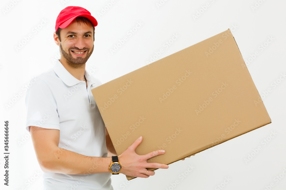 Tableau sur toile Smiling young delivery man holding and carrying a cardbox isolated on white back