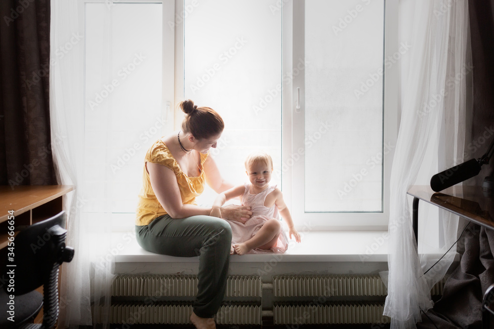 Mom and baby read, talk on the windowsill at home Mom and baby read, talk on the windowsill at home