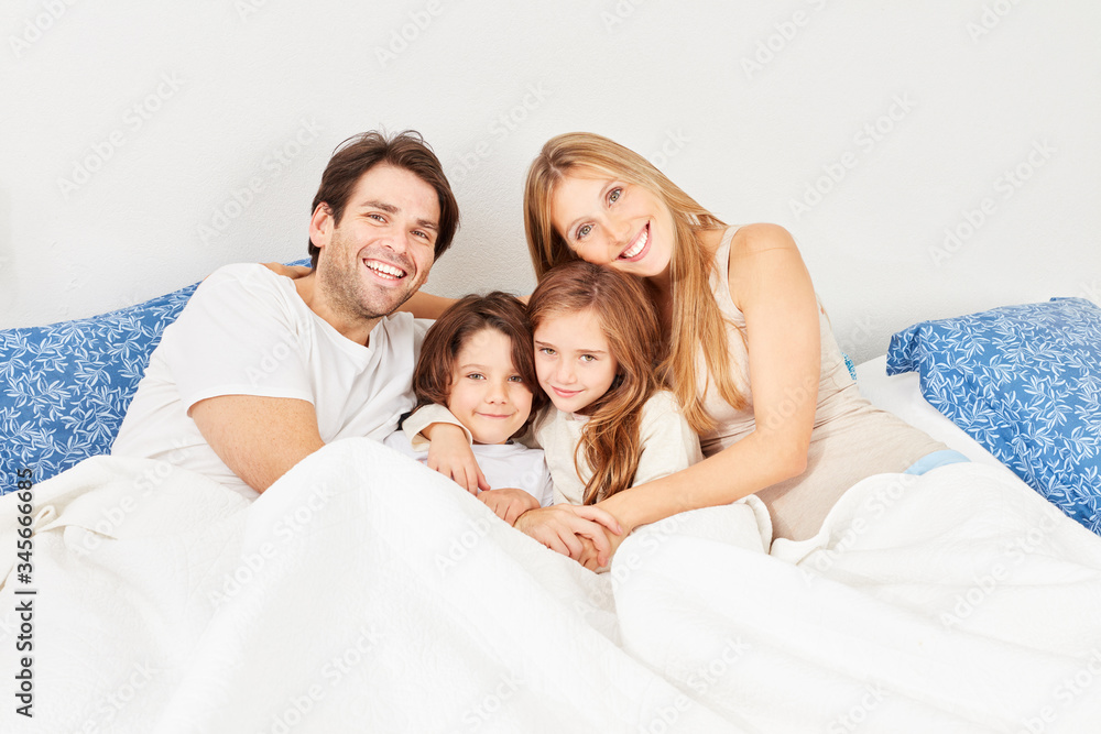 Fototapeta premium Happy parents with children together in bed