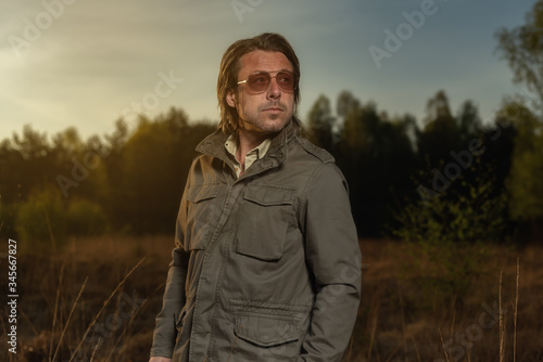 Man in green jacket and sunglasses in nature at sunrise during spring. © ysbrandcosijn