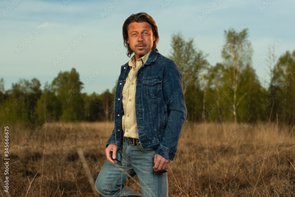 Man in jeans jacket and shirt in nature reserve at sunrise during spring.