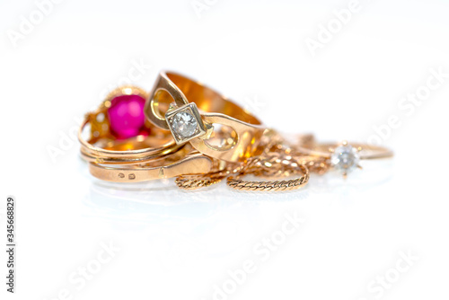 Real gold rings, diamonds , gems on white shiny surface close up macro shot.