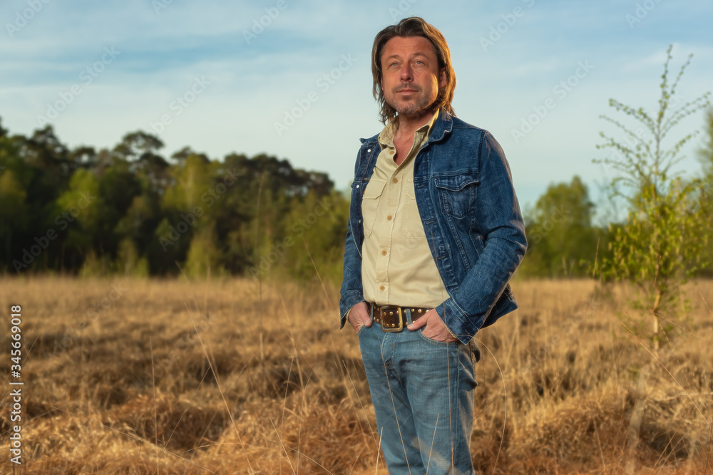 Man in jeans jacket and shirt in nature reserve at sunrise during spring. Man in jeans jacket and shirt in nature reserve at sunrise during spring.