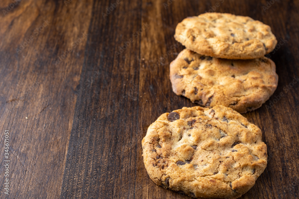 Top view of three chocolate chip cookies, with selective focus, on dark wooden table, horizontal, with copy space Top view of three chocolate chip cookies, with selective focus, on dark wooden table, horizontal, with copy space