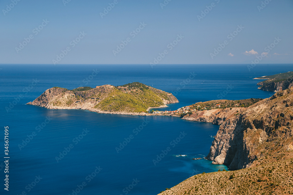 A top view at dark blue Ionian Sea, Asos village and Assos peninsula from a road. Aerial view, summer scenery of famous and extremely popular travel destination in Cephalonia, Greece, Europe.