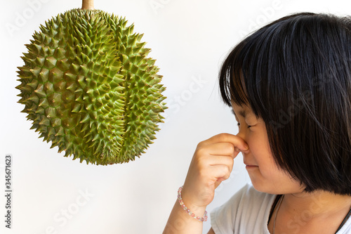 Cute girl squeeze nose in front of Durian with white background