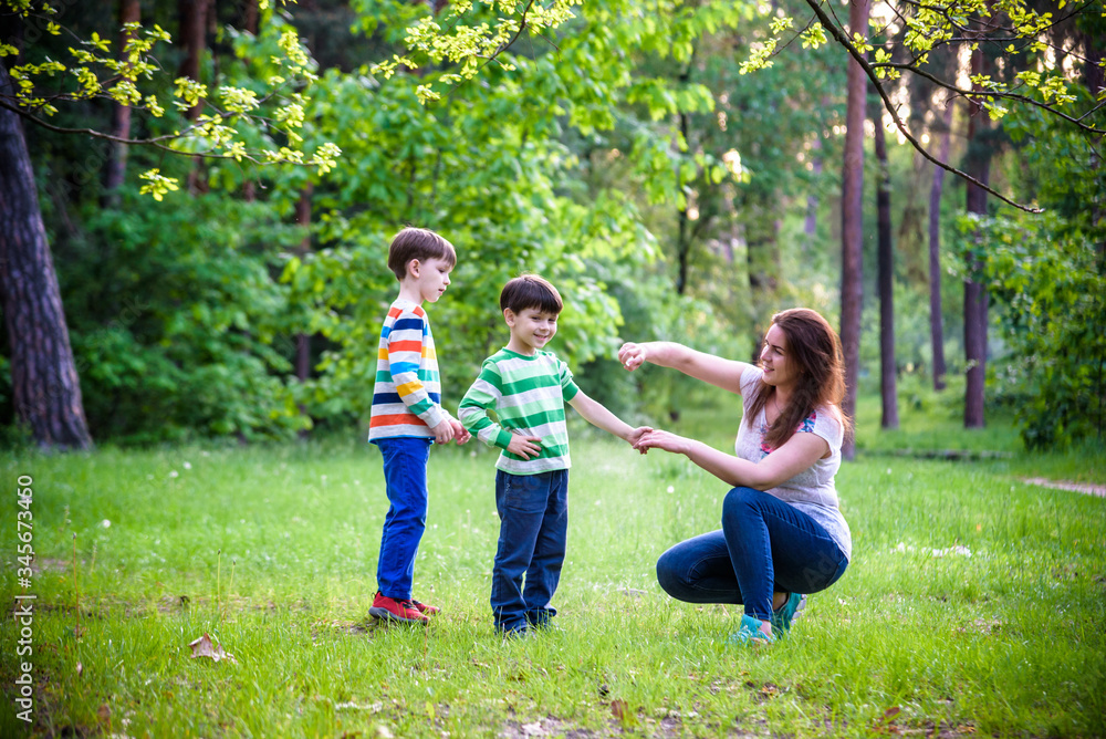 Young woman mother applying insect repellent to her two son before forest hike beautiful summer day or evening. Protecting children from biting insects at summer. Active leisure with kids Young woman mother applying insect repellent to her two son before forest hike beautiful summer day or evening. Protecting children from biting insects at summer. Active leisure with kids